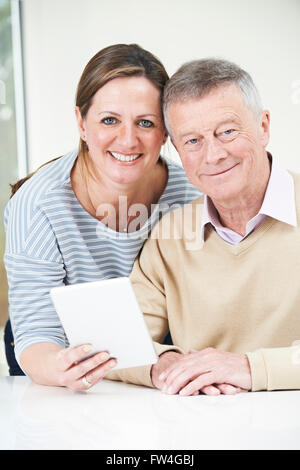Ältere Menschen und Erwachsene Tochter Blick auf Digital-Tablette zusammen Stockfoto