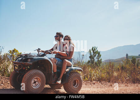 Junger Mann und Frau auf einem Quad-Bike fahren. Paar im Urlaub genießen auf einem ATV Fahrrad fahren an einem Sommertag. Stockfoto