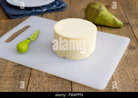 Komplettes hausgemachte Cheshire Käse auf einem alten hölzernen Küchentisch. Stockfoto