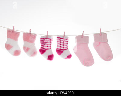 Rosa und weiße Babysocken auf der Wäscheleine, isoliert auf weißem Hintergrund Stockfoto