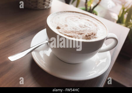 Tasse Cappuccino. Kaffee mit Milchschaum steht auf Holztisch, Vintage Tonwertkorrektur Filter, alten Stil Fotoeffekt Stockfoto