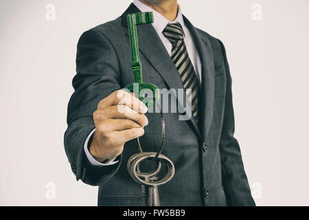 Mann im Anzug hält einen Schlüsselbund überdimensionale historische vor seinem Körper. Die analogen Film-Effekt unterstreicht das Alter Stockfoto