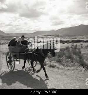 In den 1950er Jahren, historisch, tagsüber und im ländlichen Irland, reisen ein Vater, eine Mutter und ihre Jungen in einer Pferdefalle entlang einer Landstraße im Westen Irlands. Stockfoto