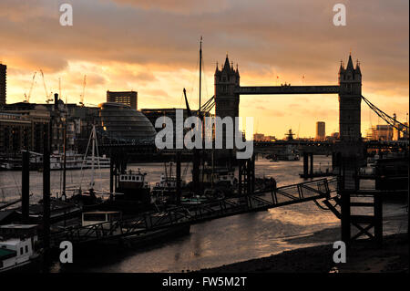 Masten und Takelage für den Versand an St Katharine Docks, von Wapping, London, Tower Bridge bei Sonnenuntergang, Winter. Begonnen 1823; Die Lagerhäuser runden dieses Dock waren nahe am Wasser gebaut, so dass Fracht von Kränen direkt vom Schiff ins Lager entladen werden konnten. Dies reduzieren das Risiko von stehlen, und so war das Dock für wertvolle Frachten wie Elfenbein, Gewürze und Marmor, etc. verwendet. Charles Dickens, englischer Schriftsteller, hatte eine lebenslange Verbindung mit Wapping und Limehouse, zahlreiche Szenen am Fluss, einschließlich Mephistopheless Hof in The Old Curiosity Shop und Kapitän Cuttle Haus in Domb einstellen Stockfoto