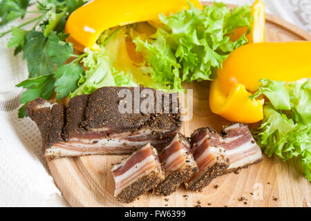 Eine köstliche geräucherte Rippchen mit Gewürzen rund um frische gelbe Paprika Salat Blätter Petersilie on Board und Serviette White Stockfoto