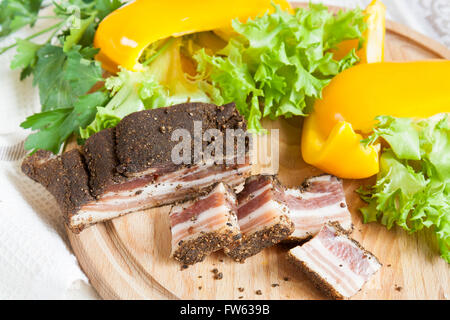 Eine köstliche geräucherte Rippchen mit Gewürzen rund um frische gelbe Paprika Salat Blätter Petersilie on Board und Serviette White Stockfoto