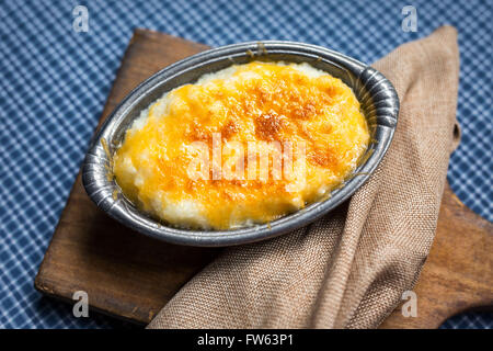 Overhead shot von hominy Grits gebacken mit Cheddar Käse in eine kleine antike Zinn Schüssel servieren. Stockfoto