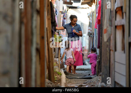 Frau, ca. 40, mit Enkel in einer schmalen Gasse zwischen den Baracken ein Slum, Favela 21 de Abril, São Paulo, Brasilien Stockfoto