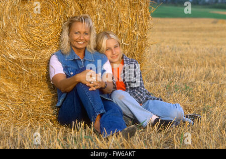 Mutter und Tochter in einem Feld gelehnt Rundballen Heu Stockfoto