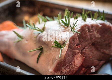 Rohe Lammkeule - Raw Frühling Lammkeule in einen Bräter mit Rosmarin und Knoblauch, flachen Fokus besetzt. Stockfoto