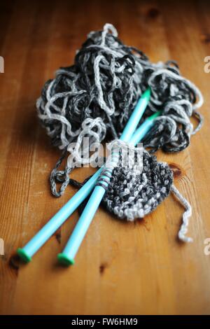 Strickende Nadeln und Garn mit einem teilweise gestrickten Schal. Stockfoto