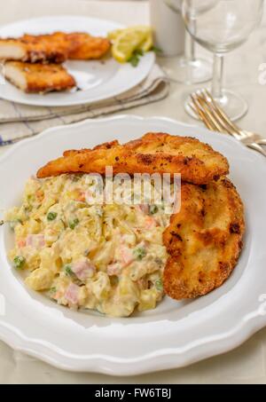 Tschechische traditionelle Schnitzel mit Kartoffeln und Gemüse Salat auf weißen Tisch Stockfoto