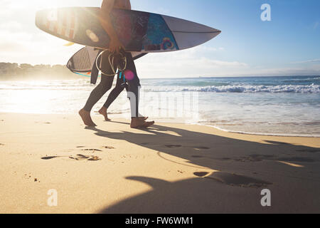 Australische Surfer Jungs entlang Bondi Beach mit Surfbrettern und Sonne flare Stockfoto