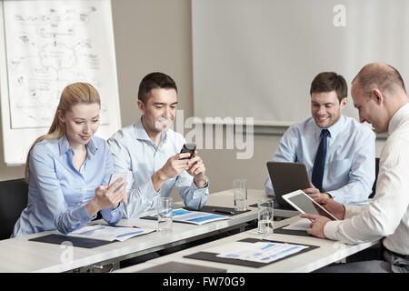 Lächelnde Geschäftsleute mit Gadgets im Büro Stockfoto
