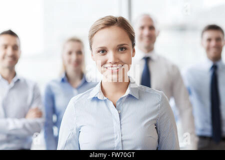 lächelnde Geschäftsfrau mit Kollegen im Büro Stockfoto
