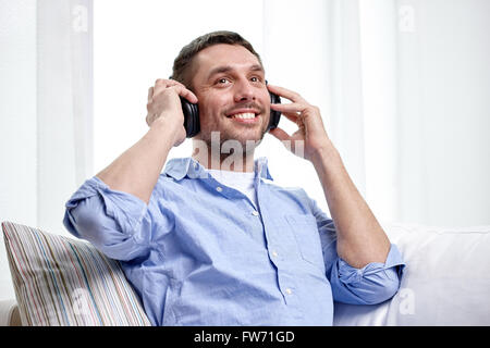 lächelnder junge Mann im Kopfhörer zu Hause Stockfoto