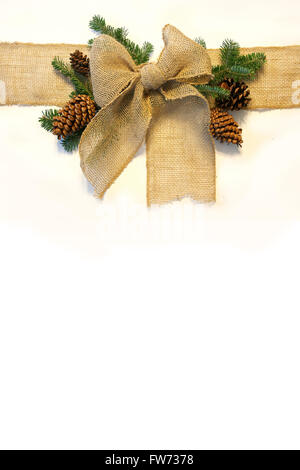 Ein Sackleinen-Webband ist auf einem weißen Hintergrund, umgeben von Tannenzapfen und Immergrüner Weihnachtsbaum Äste isoliert. Stockfoto