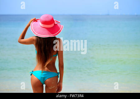 Frau in großen Hut sitzt am Strand am Meer Stockfoto