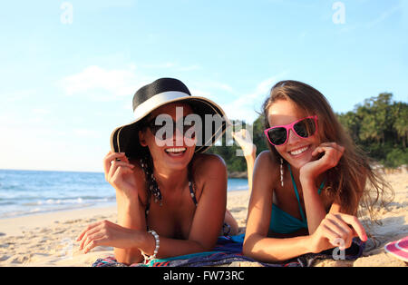 Glücklich lächelnd Freundinnen am tropischen Strand liegen Stockfoto