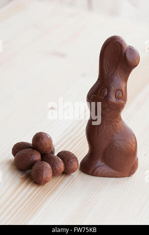 Unverpackte Chokolade Osterhase mit Eiern auf einem Holztisch Stockfoto