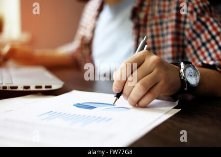 Close up Portrait of Business Mann Hand arbeiten auf Laptop-Computer mit Business Graph Informationen Diagramm auf Schreibtisch aus Holz Stockfoto