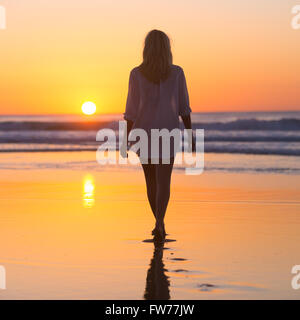 Dame zu Fuß am Strand im Sonnenuntergang. Stockfoto