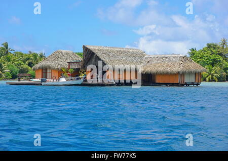 Tropischen Heimat über Wasser mit Strohdach und einem Boot im Dock, Huahine Insel, Pazifik, Französisch-Polynesien Stockfoto