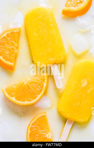 Hausgemachte, natürliche Orange, erfrischende Sommer Eis am Stiel. Von oben flach lag auf weißem Marmor mit frischen Orangenscheiben. Stockfoto