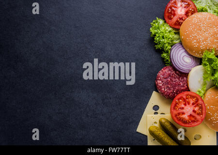 Dunkelrestaurant Menü, Burger-Zutaten und Textfreiraum. Dunkler Schiefer von oben. Stockfoto