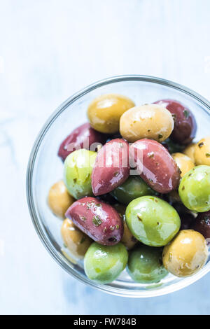 Frische ganze Oliven in Schüssel geben, mit Öl und Gewürzen. Spanische Tapas-Konzept. Stockfoto