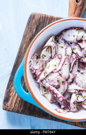 Oktopus Capraccio in traditionellen Tapas Keramikschale, von oben auf Holzbrett Stockfoto