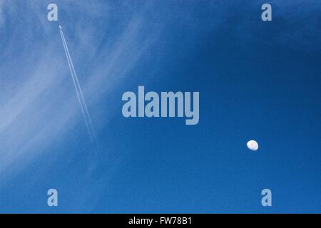 Waxing/abnehmenden Mond gegen blauen Himmel mit Wolken und Jet Trails. Stockfoto