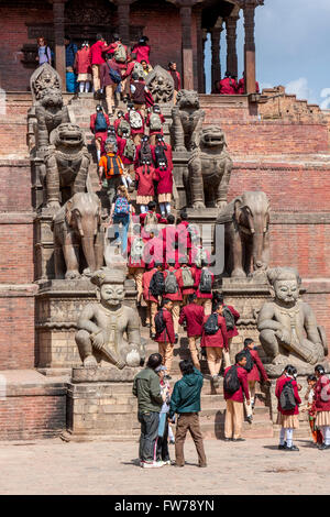 Bhaktapur, Nepal.  Nepalesische Studenten in Uniform der Nyatapola-Tempel besuchen.  Wächter säumen die Schritte. Stockfoto