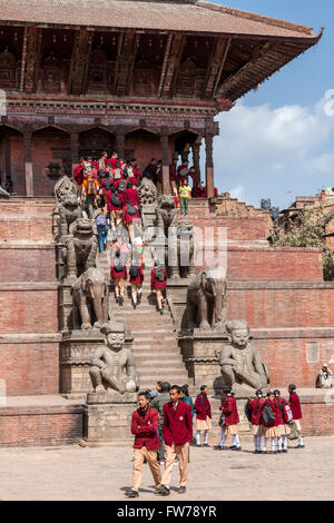 Bhaktapur, Nepal.  Nepalesische Studenten in Uniform der Nyatapola-Tempel besuchen.  Wächter säumen die Schritte. Stockfoto