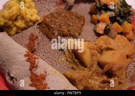 Eine Rolle der Injera Roll ist ein Sauerteig - auferstandenen Fladenbrot mit einer einzigartigen, leicht schwammig Textur mit traditionellen Äthiopischen Eintöpfe und Gemüse serviert. Stockfoto