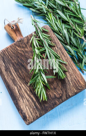 Frischer Rosmarin Kräuter auf blau lackierten Pastell Holztisch, lay-flat von oben Stockfoto