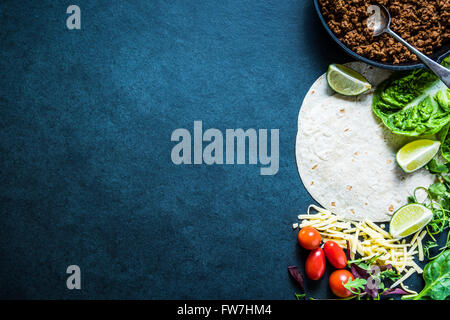 Mexikanische Fajitas oder Tortillas, Essen Rand Hintergrund mit Platz für Text oder Rezept. Overhead auf dunklen Schiefer. Stockfoto