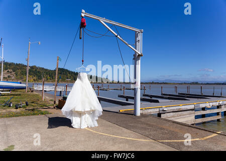 Brautkleid hing aus ein Boot Hebezeug in einer Yach Club Marina, bevor die Braut legt es auf. Stockfoto