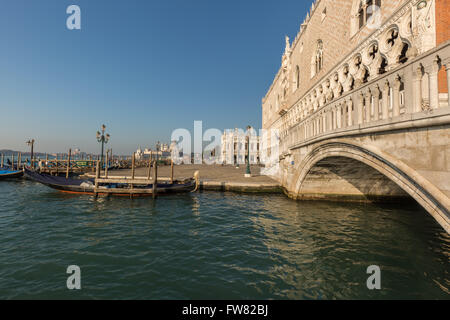 Eine Brücke neben dem Dogenpalast in der Nähe von Markusplatz in Venedig über den Kanal auf einem festgemachten Gondel und einen Blick auf Basilika Stockfoto