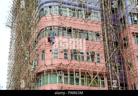 Ein Gebäude mit Bambus-Gerüst in Kowloon, Hongkong. Da Bambus viel billiger als Stahl, aber nur so stark ist, ist es meist für den Gerüstbau in Asien verwendet. Stockfoto