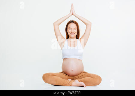 Lächelnde schwangeren Yoga Übung auf dem Boden isoliert auf weißem Hintergrund Stockfoto