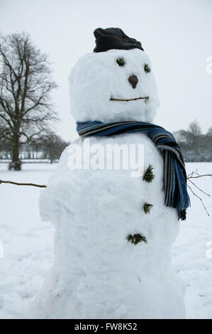 Ein Schneemann im frisch gefallenen Schnee von einem britischen Winter allein in einem Park in Gloucestershire Stadt von Cirencester im Vereinigten Königreich gemacht. Stockfoto