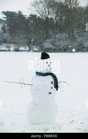 Ein Schneemann im frisch gefallenen Schnee von einem britischen Winter allein in einem Park in Gloucestershire Stadt von Cirencester im Vereinigten Königreich gemacht. Stockfoto