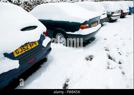 Geparkte Autos in einer dicken Schicht Schnee bedeckt, so dass sie nahezu unsichtbar sind speichern für Räder und Stoßstangen unter die gefrorene weiße Decke zeigt. Stockfoto