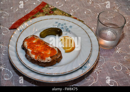Roter Kaviar auf Scheibe Schwarzbrot, Glas Wodka, Gurke und Zitronenscheibe. Clipping-Pfad enthalten. Stockfoto