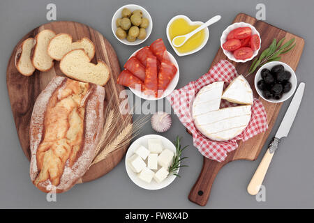 Frische Lebensmittel-Auswahl mit Chorizio, Camembert und Feta-Käse, Oliven, Tomaten, Olivenöl, Kräuter und Bauernbrot auf Ahorn-Boards. Stockfoto