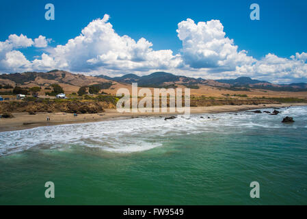 Rückblick auf Ufer die Wellen gegen die Küste, weiße Schaum zu brechen, blaue grünes Meer, Berge, blauer Himmel, Wolken. Stockfoto