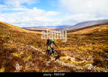 Mountainbiker auf Moorland über Glen Coulin in Torridon Highland Schottland mit den Gipfeln des Fannichs in der Ferne Stockfoto