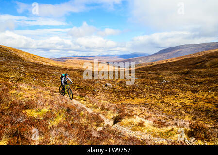 Mountainbiker auf Moorland über Glen Coulin in Torridon Highland Schottland mit den Gipfeln des Fannichs in der Ferne Stockfoto