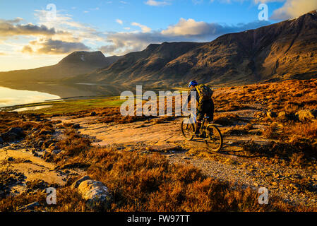 Mountainbiker absteigend in Richtung Loch Torridon Highland Schottland mit den unteren Hängen des Gipfelns auf R und Beinn Alligin hinter Stockfoto